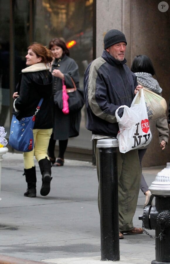 Richard Gere en SDF, tournant incognito près de Grand Central à Manhattan, vient de recevoir les restes d'une pizza de la part d'une touriste française (que l'on voit derrière, avec le sac bleu, à New York, le 22 avril 2014.