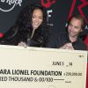 Rihanna, tout heureuse de recevoir le chèque de 200 000 dollars du Hard Rock Cafe pour la Clara Lionel Foundation, dont elle est la fondatrice. Paris, le 5 juin 2014.