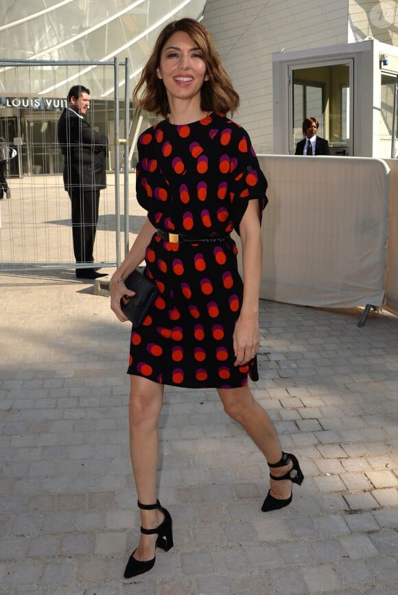 Sofia Coppola quitte la Fondation Louis Vuitton à l'issue du défilé Louis Vuitton, tout de Louis Vuitton vêtue avec une robe et des sandales de la collection croisière 2015, et une pochette noire (modèle SC Slim). Paris, le 1er octobre 2014.