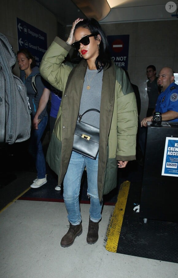 La chanteuse Rihanna arrive à l'aéroport LAX, habillée d'un manteau kaki et matelassé Isabel Marant Étoile, d'un t-shirt gris, d'un jean Balmain et de bottines Timberland. Des lunettes de soleil Ray-Ban et un sac Balenciaga (modèle Le Dix) accessoirisent son look. Los Angeles, le 27 septembre 2014.