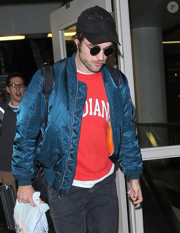 Exclusif - Robert Pattinson a une moustache et une barbe de quelques jours à son arrivée à l'aéroport deLAX à Los Angeles, le 24 octobre 2014.