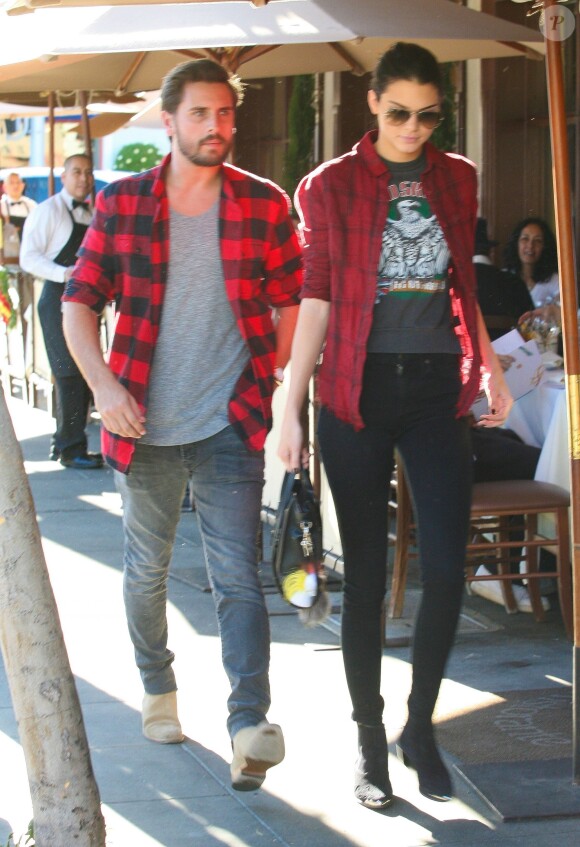 Kendall Jenner à Los Angeles avec Scott Disick, porte une chemise à carreaux RtA, un t-shirt rock vintage, un jean noir, un sac Céline accessoirisé d'un Karlito de Fendi, et des bottines Saint Laurent. Le 25 novembre 2014.