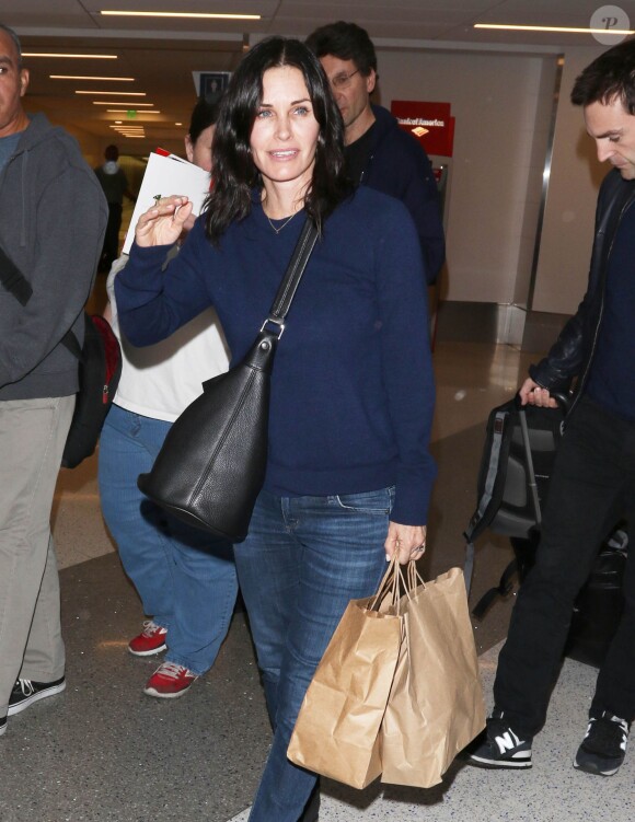 Courteney Cox et son fiancé Johnny McDaid à l'aéroport de Los Angeles, le 17 décembre 2014. Le couple semble heureux à leur retour d'un voyage romantique au cours duquel ils ont visité des caves au nord de la Californie.