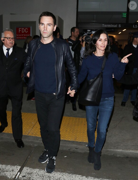 Courteney Cox et son fiancé Johnny McDaid à l'aéroport de Los Angeles, le 17 décembre 2014. Le couple semble heureux à leur retour d'un voyage romantique au cours duquel ils ont visité des caves au nord de la Californie.