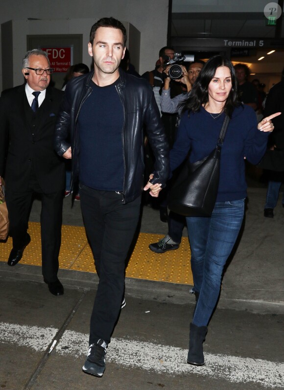 Courteney Cox et son fiancé Johnny McDaid à l'aéroport de Los Angeles, le 17 décembre 2014. Le couple semble heureux à leur retour d'un voyage romantique au cours duquel ils ont visité des caves au nord de la Californie.