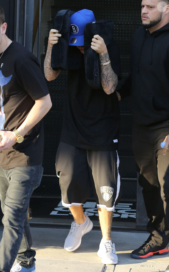 Justin Bieber se cache des photographes à la sortie d'un salon de coiffure à West Hollywood, le 27 janvier 2015