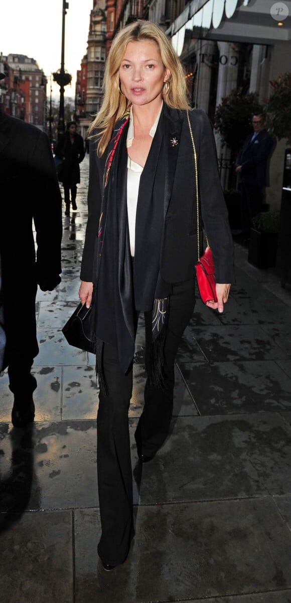 Kate Moss fait du shopping dans le quartier de Mayfair à Londres, habillée d'un tailleur-pantalon noir, d'une chemise blanche, d'un sac Bulgari ((modèle Serpenti) et de chaussures Alaïa. Le 24 mars 2015.