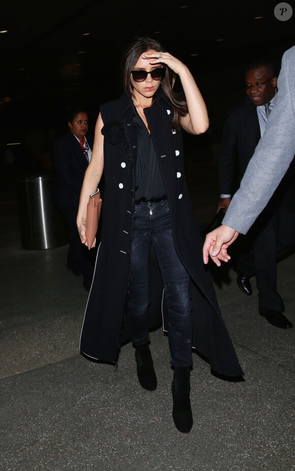 Victoria Beckham arrive à l'aéroport de Los Angeles, habillée d'un manteau noir sans manches, d'un chemisier noir, d'une pochette Victoria Beckham, d'un jean R13 et de bottines Alaïa. Le 26 mars 2015.