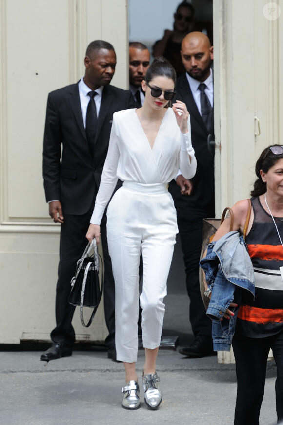 Kendall Jenner quitte le Grand Palais à l'issue du défilé Chanel haute couture, habillée d'un body et d'un pantalon Elisabetta Franchi (collection automne-hiver 2015-2016) et de chaussures argentées Barbara Bui. Des lunettes de soleil Christian Dior et un sac Saint Laurent accessoirisent sa tenue. Paris, le 7 juillet 2015.