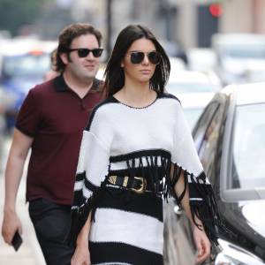 Kendall Jenner en robe noire et blanche style poncho à franges Givenchy, accessoirisée d'un sac Givenchy et d'une ceinture B-Low, à Londres le 1er juillet 2015