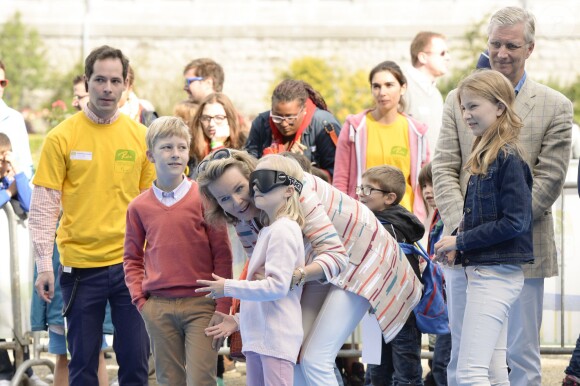 La reine Mathilde de Belgique donne des conseils à sa fille la princesse Eléonore qui s'essaye au jeu de quilles les yeux bandés, le 20 septembre 2015 à Bruxelles, dans le Parc du Cinquantenaire, à l'occasion de la 9e Fête du Sport. La famille royale participait ce jour-là au Dimanche sans voiture.