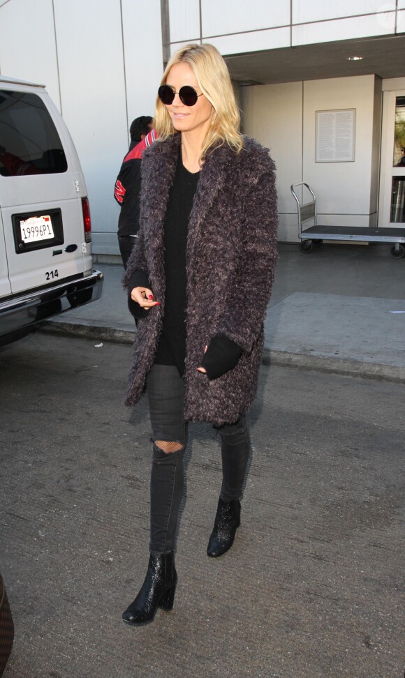 Heidi Klum à l'aéroport LAX à Los Angeles, porte des lunettes de soleil The Row, un manteau en fausse fourrure Elizabeth and James, un pull et un jean noirs, des bottines Saint Laurent. Le 12 décembre 2015.