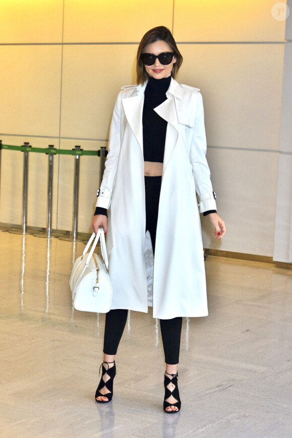 Miranda Kerr arrive à l'aéroport Narita à Tokyo, habillée d'un trench-coat ivoire Barneys New York, d'un pull court à col roulé et d'un jean noirs, et de chaussures Aquazurra (modèle Pasadena). Le 12 avril 2016.