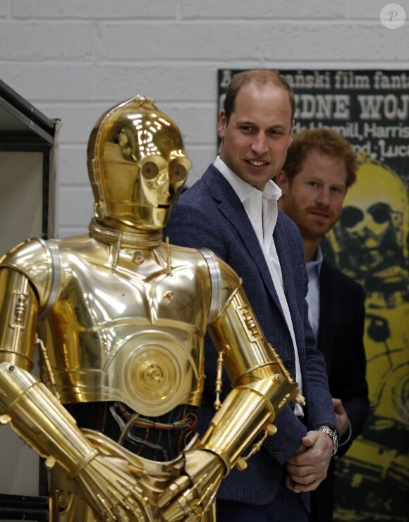 Le prince William et le prince Harry regardent le droïde de protocole C-3PO lors de leur visite des coulisses du tournage de Star Wars des studios Pinewood le 19 avril 2016.