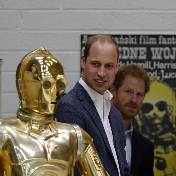 Le prince William et le prince Harry regardent le droïde de protocole C-3PO lors de leur visite des coulisses du tournage de Star Wars des studios Pinewood le 19 avril 2016.