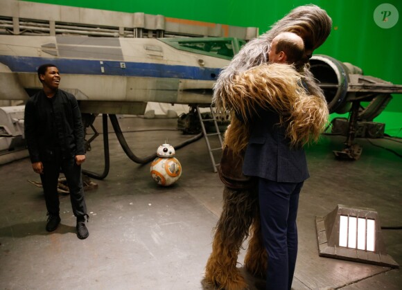 Le prince William fait un câlin à Chewbacca sous l'oeil amusé de l'acteur John Boyega lors de sa visite des coulisses du tournage de Star Wars des studios Pinewood le 19 avril 2016.