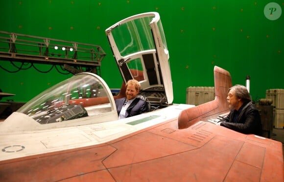 Le prince Harry se place aux commandes d'un A-Wing Fighter sous l'oeil amusé de l'acteur Mark Hamill lors de sa visite des coulisses du tournage de Star Wars des studios Pinewood le 19 avril 2016.