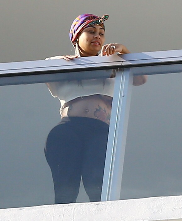 Exclusif - Blac Chyna enceinte, avec un t-shirt très court et sans soutien gorge, laisse entrevoir son ventre déjà bien rond et le dessous de ses seins au balcon de sa suite à Miami, le 16 mai 2016