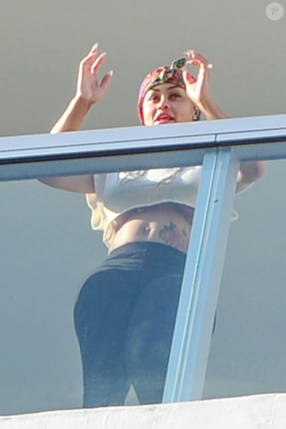 Exclusif - La compagne de Rob Kardashian Blac Chyna enceinte, avec un t-shirt très court et sans soutien gorge, laisse entrevoir son ventre déjà bien rond et le dessous de ses seins au balcon de sa chambre d'hôtel à Miami, le 16 mai 2016