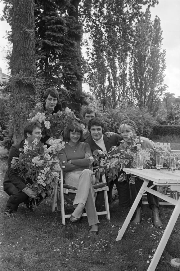 Archives - Anne-Marie Peysson, assise au centre entourée de ses amis avec des fleurs, dont Michel Delpech (en haut à gauche), Gérard Bourgeois et Jacqueline Huet à Croissy-sur-Seine, le 1er mai 1968 dans le jardin de la maison d'Anne-Marie Peysson, qui prépare la sortie de son deuxième album.