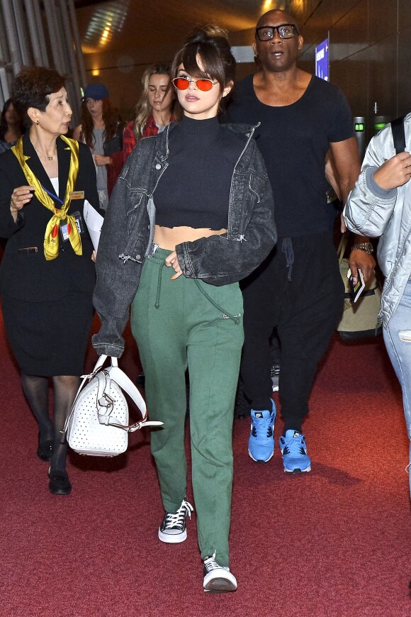 Selena Gomez à l'aéroport de Narita à Tokyo, habillée d'une veste Sami Miro Vintage, d'un crop top, d'un jogging Vetements (collection printemps-été 2016) et de baskets Converse. Un sac Louis Vuitton (modèle SC) et des lunettes de soleil complètent sa tenue. Le 1er août 2016.