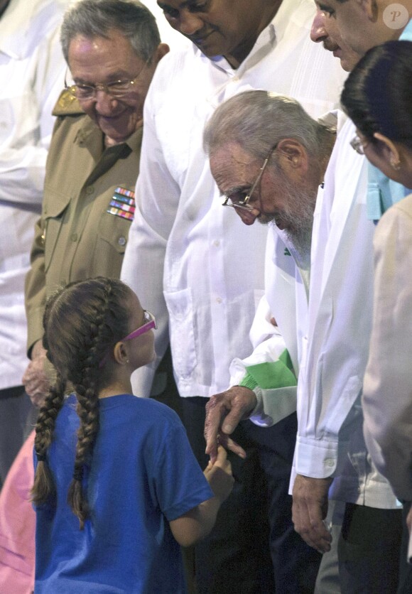 L'ancien président cubain Fidel Castro salut une petite fille à côté de de son frère le président cubain Raul Castro lors de la fête organisée pour ses 90 ans au théâtre Karl Marx à la Havane, le 13 août 2016.