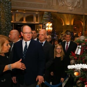 Le prince Albert II de Monaco accompagné par Louisette Levy-Soussan Azzoaglio, la présidente d'Action Innocence Monaco, pendant la traditionnelle vente aux enchères de Sapins de Noël de l'association spécialement créés et décorés pour l'occasion par de grandes marques, des boutiques et artisans de la Principauté le 14 décembre 2016 à Monaco.