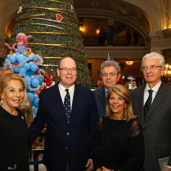 Le prince Albert II de Monaco accompagné par Louisette Levy-Soussan Azzoaglio, la présidente d'Action Innocence Monaco, pendant la traditionnelle vente aux enchères de Sapins de Noël de l'association spécialement créés et décorés pour l'occasion par de grandes marques, des boutiques et artisans de la Principauté le 14 décembre 2016 à Monaco.