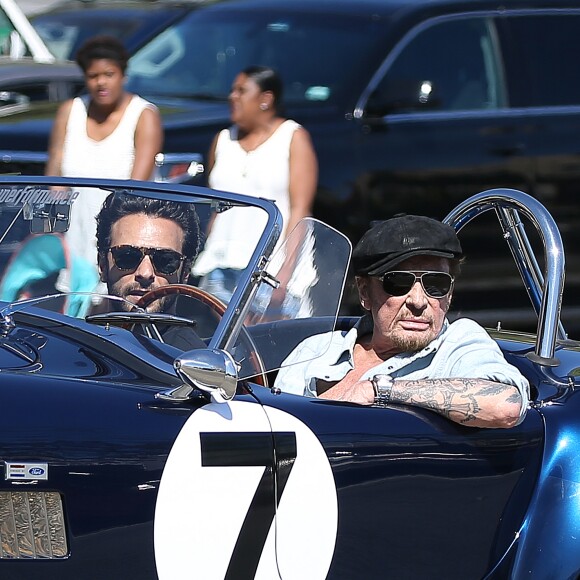 Johnny Hallyday accompagné de Maxim Nucci (Yodelice), arrive au restaurant "Soho House" à Malibu, au volant de son cabriolet AC Cobra marqué de son chiffre porte-bonheur, le numéro 7. Laeticia Hallyday, toujours en béquilles, les rejoint dans une autre voiture. Malibu, le 09 mars 2017. J
