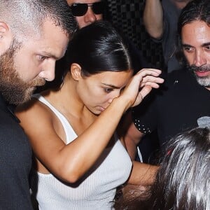 Kim Kardashian arrive chez un médecin à New York protégée par une très grosse équipe de sécurité le 11 juillet 2017. Elle porte un débardeur blanc transparent.