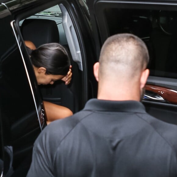 Kim Kardashian arrive chez un médecin à New York protégée par une très grosse équipe de sécurité le 11 juillet 2017. Elle porte un débardeur blanc transparent.