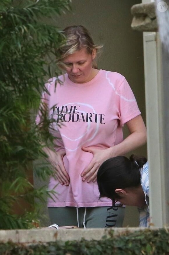 Exclusif - Kirsten Dunst change de t-shirt et se touche le ventre dans les rues de Los Angeles. Le 9 décembre 2017