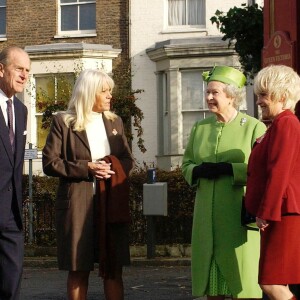 Barbara Windsor (en tailleur rouge) recevant la visite de la reine Elizabeth II et du duc d'Edimbourg sur le tournage du soap opera EastEnders en novembre 2001 à Londres.