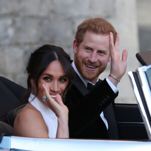 Le prince Harry, duc de Sussex, et Meghan Markle, duchesse de Sussex, habillée d'une robe Stella McCartney et portant une bague sertie d'une aigue-marine ayant appartenu à Lady Diana, quittant le château de Windsor après la réception offerte par Elizabeth II pour rejoindre à bord d'une Jaguar E-Type Concept Zero immatriculée "190518" Frogmore House où avait lieu la réception de leur mariage, le 19 mai 2018.