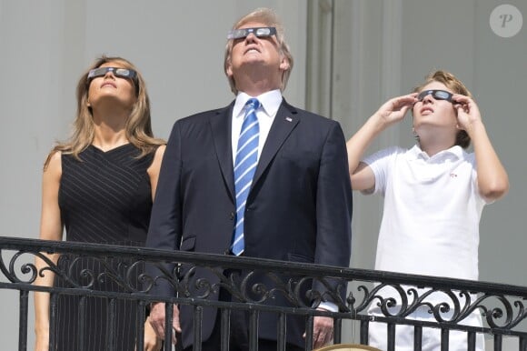 Le président Donald Trump, sa femme Melania Trump et leur fils Barron Trump regardent l'éclipse solaire totale au balcon présidentiel de la maison Blanche à Washington, The District, Etats-Unis, le 21 août 2017.