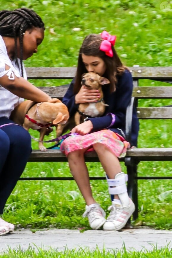 Suri Cruise, une attelle à la cheville, joue avec ses chiens dans un parc à New York, le 23 juin 2018.