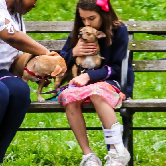 Suri Cruise, une attelle à la cheville, joue avec ses chiens dans un parc à New York, le 23 juin 2018.