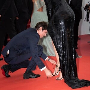 Niels Schneider rattachant la chaussure de Virginie Efira lors de la montée des marches du film Sibyl au Festival de Cannes le 24 mai 2019