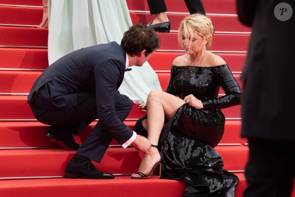 Niels Schneider rattachant la chaussure de Virginie Efira lors de la montée des marches du film Sibyl au Festival de Cannes le 24 mai 2019