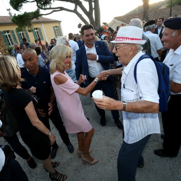 Semi-Exclusif - Brigitte Macron danse avec un vacancier - Le Président de la République Emmanuel Macron et sa femme la Première Dame Brigitte Macron (Trogneux) ont participé à un pot de l'amitié suivi d'un bain de foule sur la place centrale du village de Bormes-les-Mimosas, le 17 août 2018. © Luc Boutria / Nice Matin / Bestimage