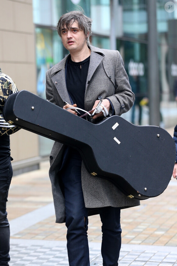 Le rocker Pete Doherty quitte les studios de la BBC après l'enregistrement de l'émission Radio Five Live, il porte un long manteau ulster en laine gris et l'étui de sa guitare à la main. Salford, le 9 mai 2019.
