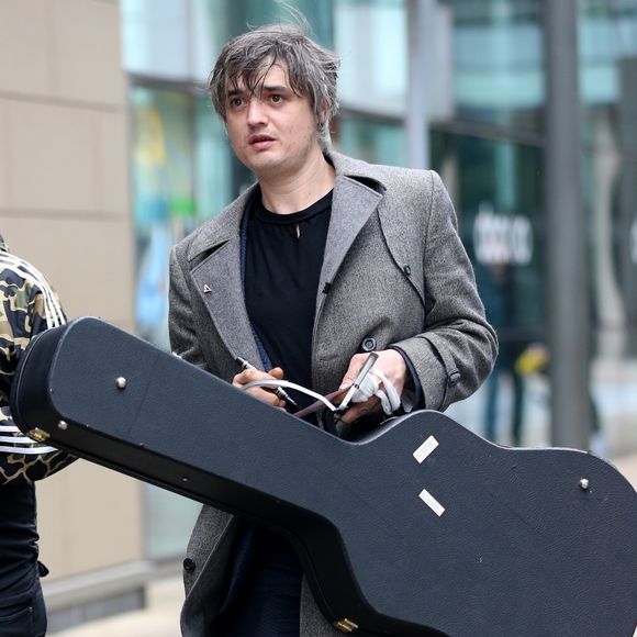 Le rocker Pete Doherty quitte les studios de la BBC après l'enregistrement de l'émission Radio Five Live, il porte un long manteau ulster en laine gris et l'étui de sa guitare à la main. Salford, le 9 mai 2019.