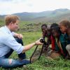 Le prince Harry d'Angleterre montre a des enfants la photo qu'il vient de prendre d'eux avec un appareil Fuji X100s pendant sa visite d'une école construite par Sentebale lors de sa visite au Lesotho à Mokhotlong, le 8 décembre 2014.
