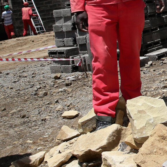 Le prince Harry d'Angleterre taille une pierre pendant sa visite de la construction du nouveau centre de Sentebale Mamohato Children's Centre à Thaba-Bosiu à Maseru, le 6 décembre 2014.