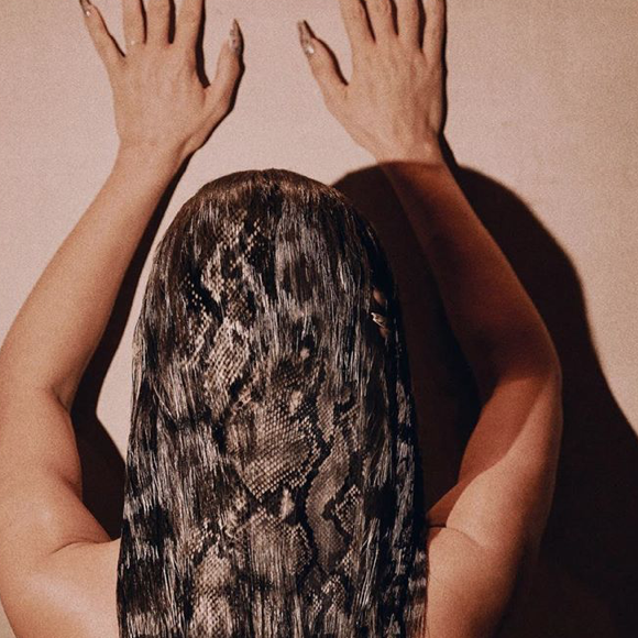 Kim Kardashian a-t-elle laissé un doigt dans ses cheveux, alors que ses deux mains sont collées au mur ? Photo par Greg Swales. Mai 2020.