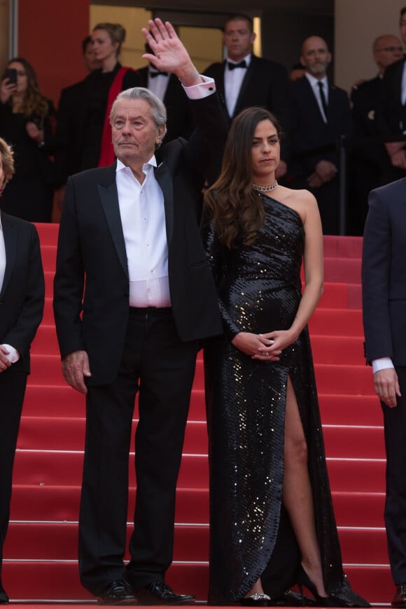 Alain Delon (Palme d'Or d'Honneur du 72ème festival de Cannes avec un badge Paris Match d'une ancienne couverture du magazine titrant "Alain Delon, mes deux amours, Rosalie et Anouchka) et sa fille Anouchka (Robe Elie Saab) - Montée des marches du film "A Hidden Life" lors du 72ème Festival International du Film de Cannes. Le 19 mai 2019.