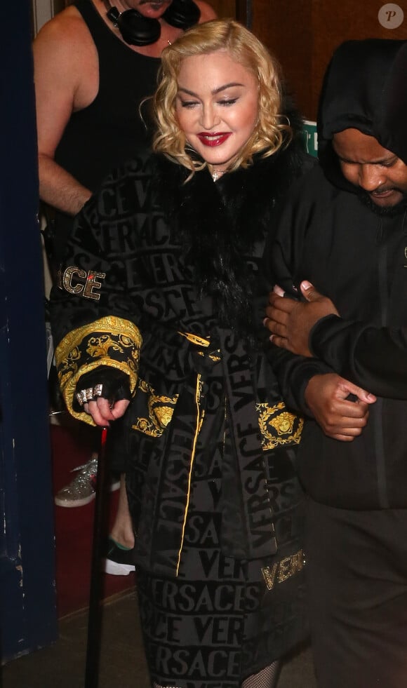 Madonna porte un manteau Versace et marche à l'aide d'une canne à la sortie du London Palladium à Londres. Le 16 février 2020.
