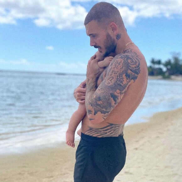 M. Pokora avec son fils Isaiah (10 mois) dans les bras, sur une magnifique plage de l'île Maurice le 24 octobre 2020.