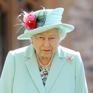 La reine Elisabeth II d'Angleterre remet au capitaine Thomas Moore son titre de chevalier lors d'une cérémonie au château de Windsor, le 17 juillet 2020. Il pose ensuite avec sa famille.