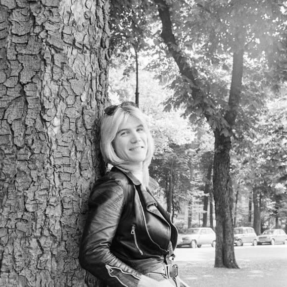 En France, à Paris, portrait de Patrick Juvet en blouson de cuir, une paire de lunettes de soleil sur son front, adossé contre un arbre, souriant en extérieur . Le 14 mai 1974. © Bruno Schneider via Bestimage